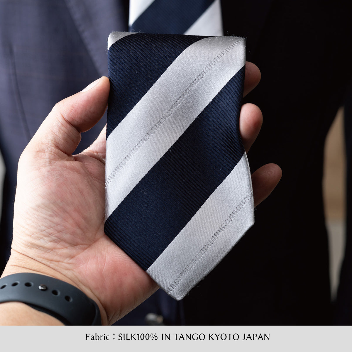 シルクネクタイ（ネイビー×シルバー）を手に持った斜めストライプ