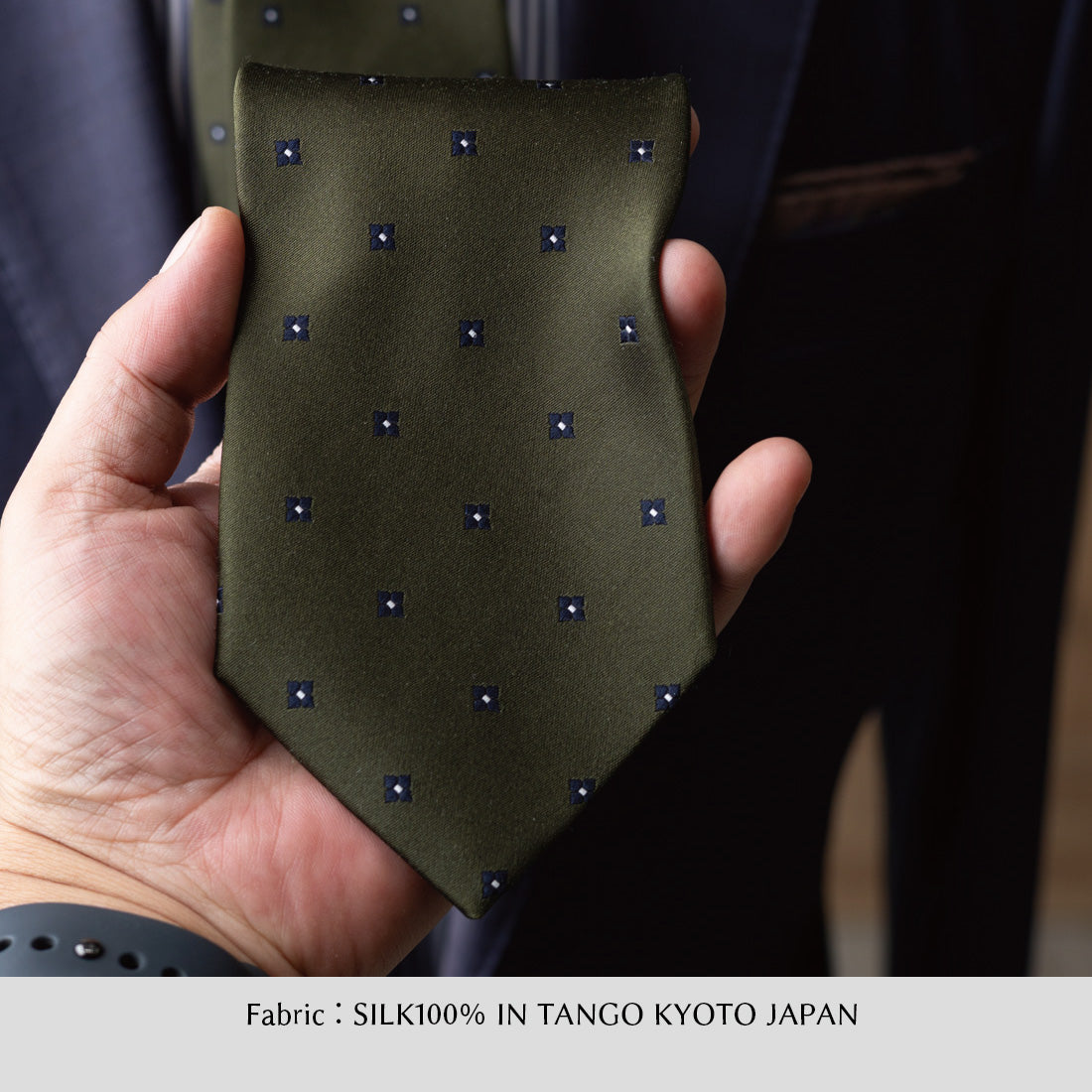 オリーブの小紋柄シルクサテンネクタイ、細かな青い四角モチーフが点在